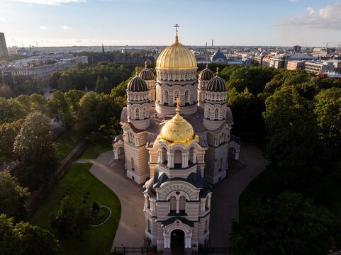 Nativity of Christ Cathedral front view with park from drone, Riga, Latvia. Aerial view of the striped facade, arched windows and gilded domes of the orthodox church seen from the front.