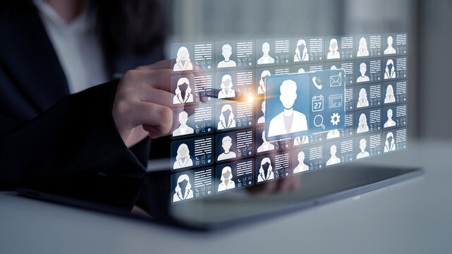 Professional woman interacting with digital interface showcasing multiple user profiles and digital information in modern work environment. Entropy.