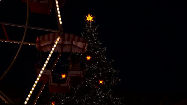 Christmas tree and ferris wheel at holiday market at night. Festive christmas market scene at night featuring a beautifully decorated and illuminated christmas tree with star ornaments