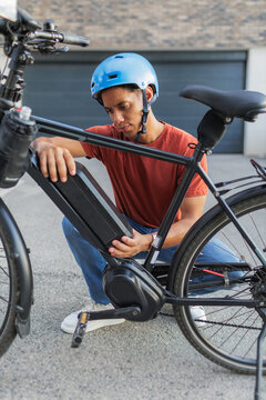 Electric bicycle battery maintenance, man changing power pack on e-bike outdoors