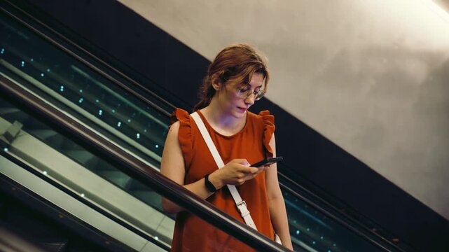 A woman tourist comes up the escalator and looks at her phone in Naples