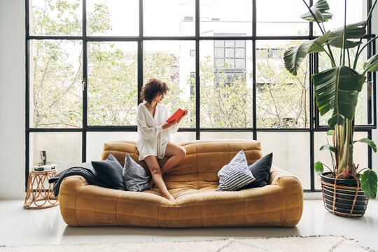 Woman reading book relaxing in modern spacious living room