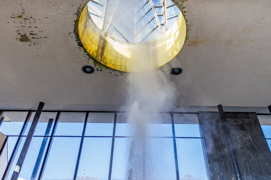 Waterfall feature in modern building atrium with skylight, geyser