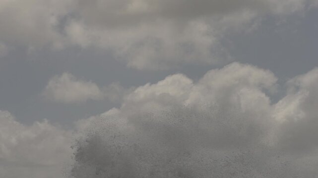 Slow Motion Vertical Tilt Down Shot of Waves Crashing Against Old Wooden Pier Posts and Exploding in Spray