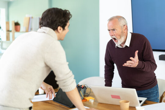 Elderly and young male colleague are arguing excitedly in office of company. Disagreements, insubordination, inconsistency of views