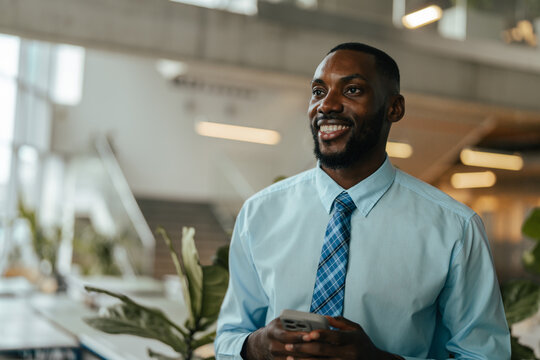 Young entrepreneur smiling holding phone in modern office