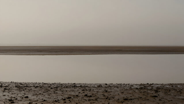 Vast flat landscape with calm water and hazy horizon