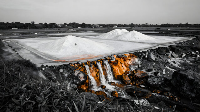 White powder piles near industrial runoff stream landscape