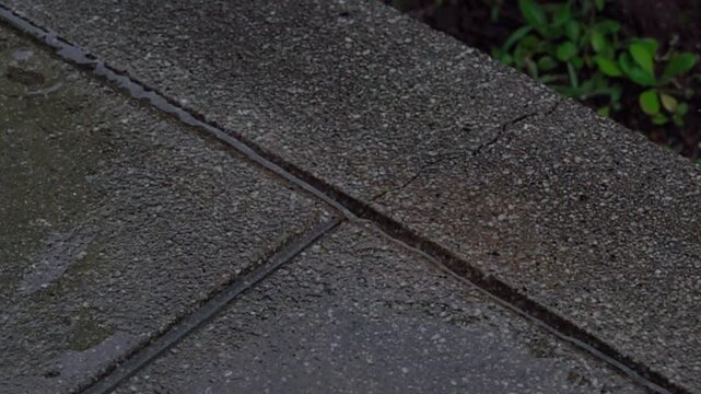 Super slow motion of large raindrop hitting concrete ground and splashing