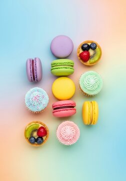 Top-down view of colorful sweet treats like macarons, cupcakes, and tarts neatly arranged on a smooth aesthetic pastel gradient background, soft, sweets, composition