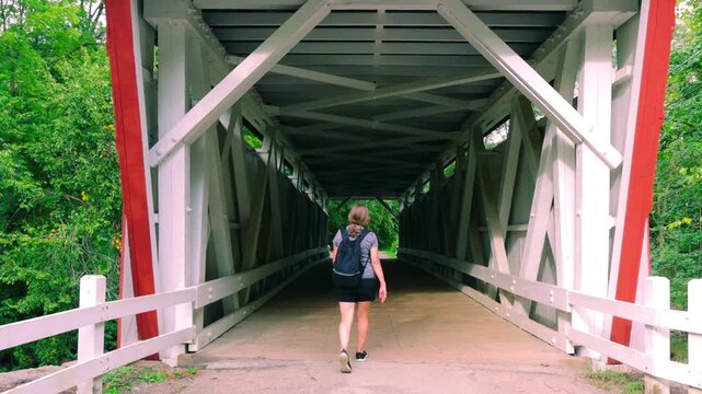 Female Hiker Crossing The Everett Covered Bridge Over Furnace Run Creek, Cuyahoga Valley National Park, Ohio, USA
