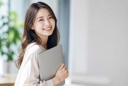 ノートパソコンを抱えて微笑む女性会社員