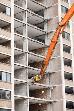 A demolition machine with mechanical arm grabbing a concrete floor of a building