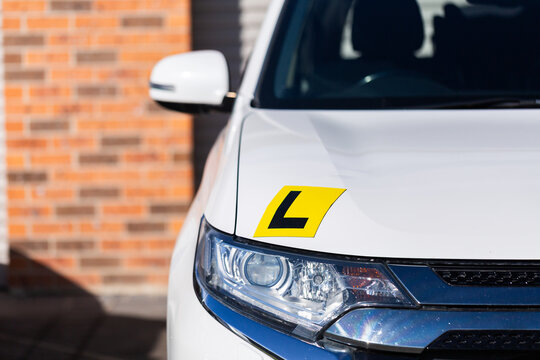 Magnetic yellow L plate for learner driver on car parked on driveway