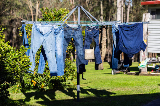 peg basket hanging on rotary washing line in backyard with denim jeans hanging on clothesline