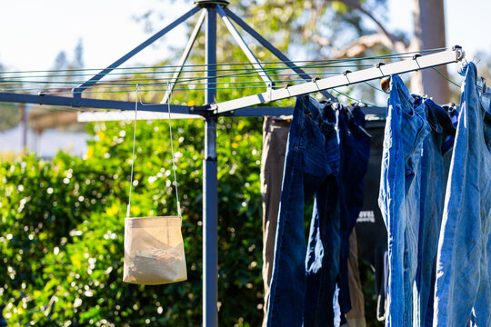peg basket hanging on rotary washing line in backyard with denim jeans hanging on clothesline