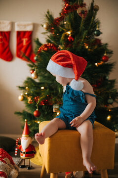 blonde girl sits on a yellow stool by a Christmas tree