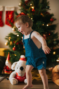 no focus image of playful blonde girl dancing happily near the Christmas tree
