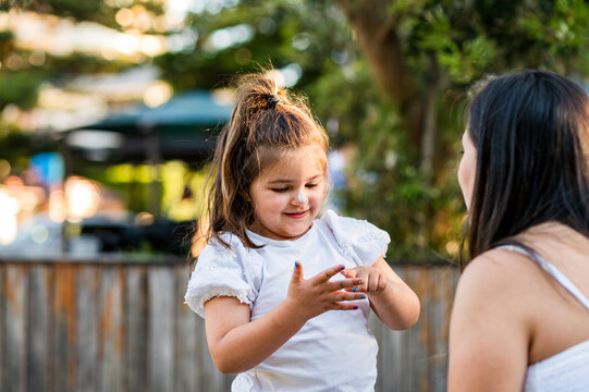 Child pointing at fingers outdoors with adult watching closely