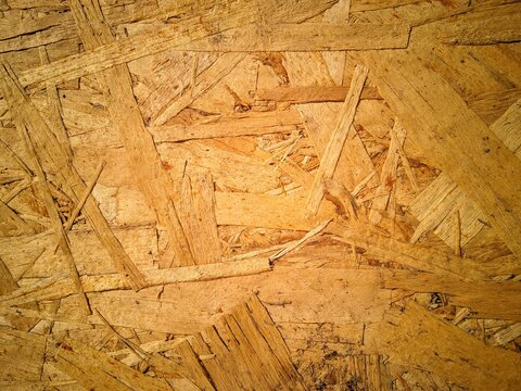Close-up texture of an Oriented Strand Board (OSB) wood panel, showing the details of the compressed wood chips for the background material.
