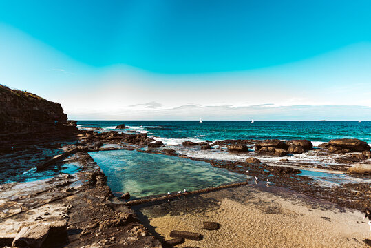natural rock pool with ocean and sailboats