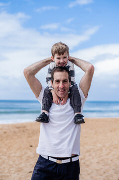 Happy father enjoys time with his young son at the beach under a clear blue sky