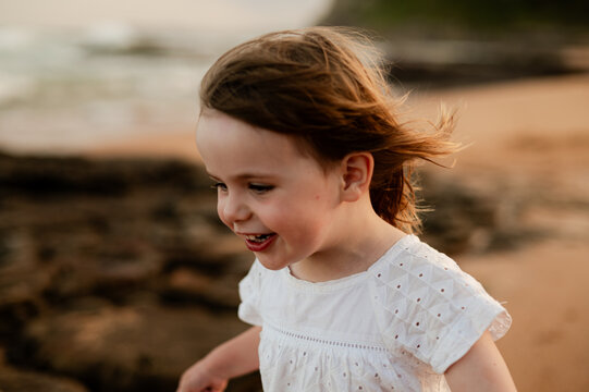 Child running on sandy beach during sunset with ocean waves in background