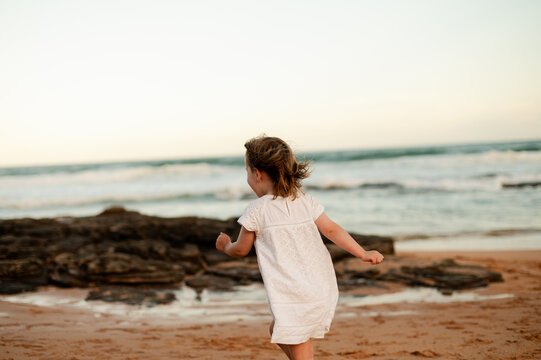 Child running along the beach at sunset, enjoying the waves and sandy shore