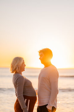 Manly Beach sunrise maternity couple embracing, expecting parents at the ocean