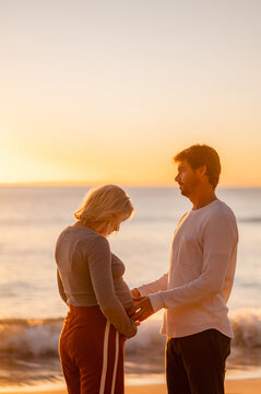 Couple celebrating pregnancy at Manly Beach during sunrise