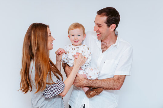 two parents playing with young child in white background