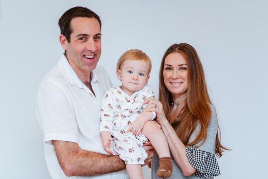 small family with mum, dad and young boy on white background smiling