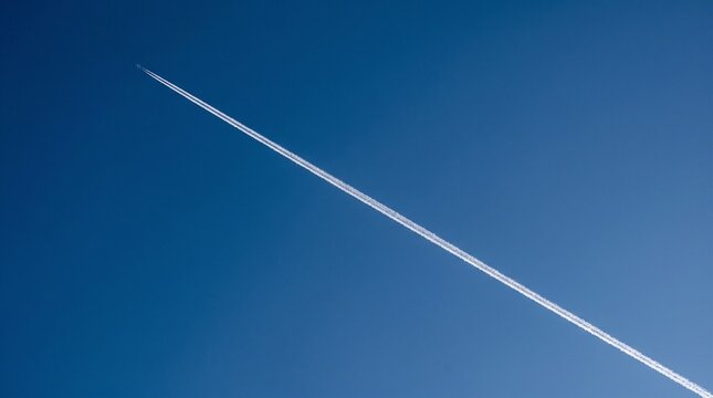 White vapor trail from an airplane crossing a clear deep blue sky