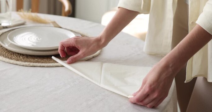 Woman folding napkin and decorating it with dry plants at table, closeup. Camera tracking and moving left