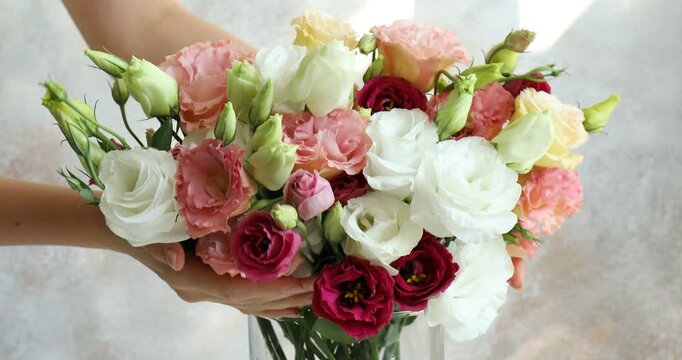Woman with bouquet of beautiful eustoma flowers indoors, closeup