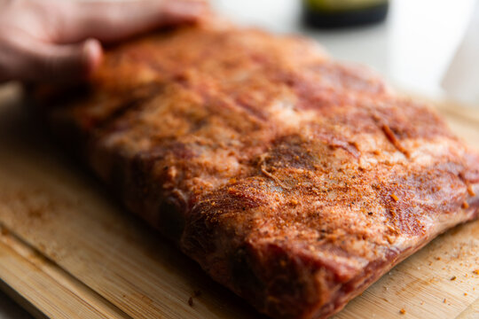 seasoning being rubbed onto a rack of beef ribs