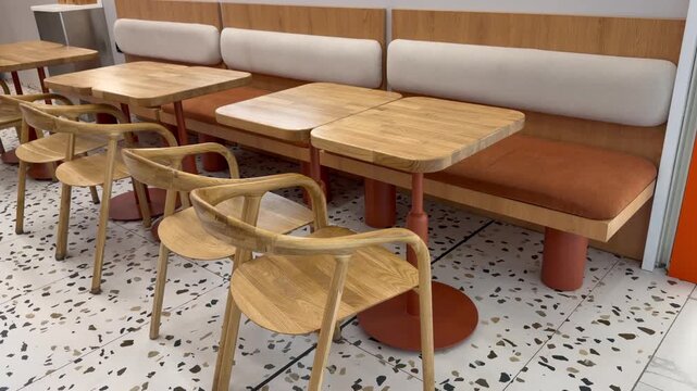 Row of wooden chairs and empty tables inside a modern cafe interior. Dining room, restaurant furniture, public eatery.