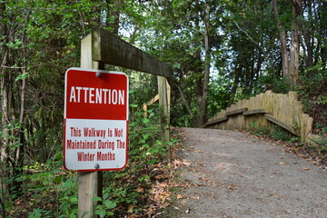 Attention warning sign on unmaintained winter trail in a public park © Yulia