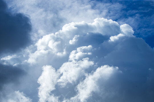 Dramatic storm clouds gathering in the bright blue sky.A stunning, high-contrast photograph capturing heavy storm clouds building up against a vibrant blue sky.