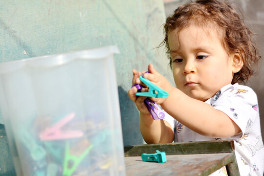 Toddler playing with clothespins.