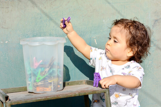 Toddler playing with clothespins.