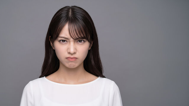 不満そうな表情でこちらを睨む若い女性