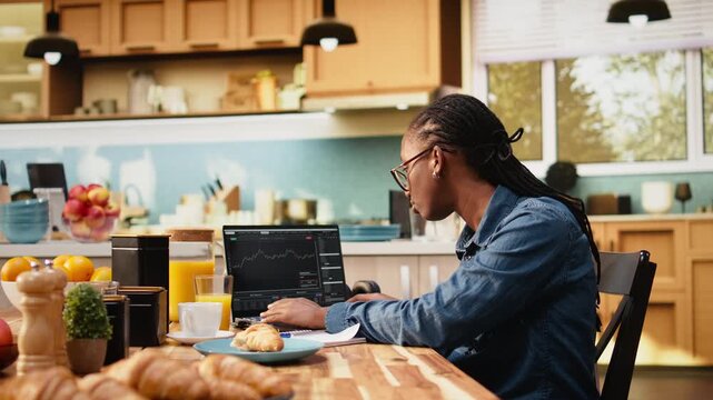 Woman investor monitors day trading price fluctuations and market trends on candlestick charts, using laptop to research investments and stock exchange while performing financial analysis for profit.