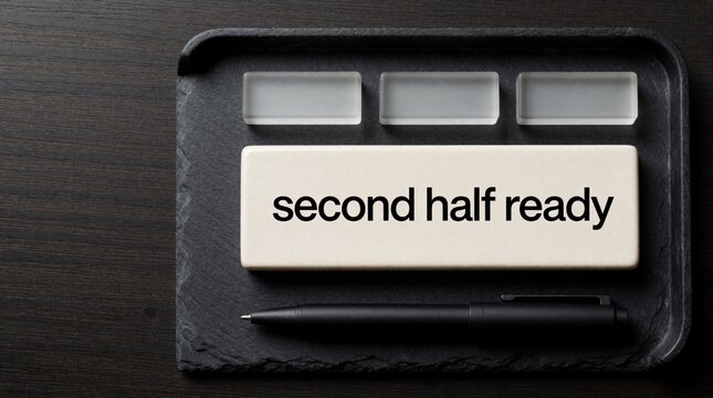 Minimal office desk setup shows ceramic title block with text second half ready. Nearby are frosted glass markers and black pen on dark slate tray. Space for text.