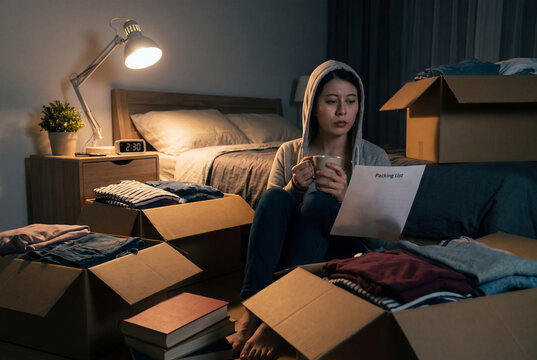 Woman sitting with tea and packing list in a dark room