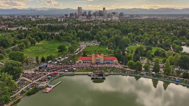 Crowds gathering at city park for an outdoor concert with denver skyline and mountains afternoon drone video 4K