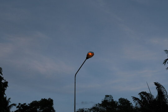 Single glowing streetlamp against a blue twilight sky