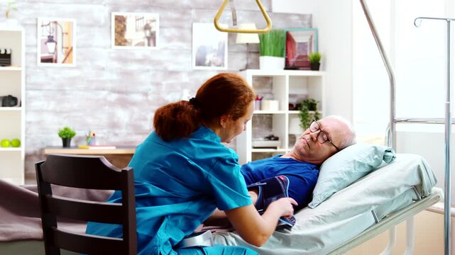 nurse places a blood pressure cuff on an older man resting in bed, documenting a routine vital-sign check and bedside healthcare for seniors.