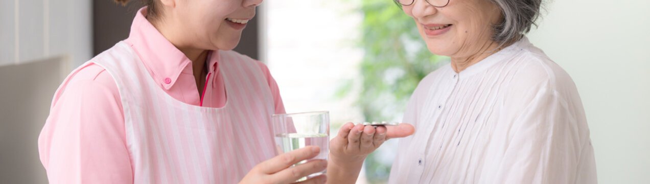 訪問介護で高齢者の服薬を支援する介護福祉士や看護師の女性ホームヘルパー、在宅介護、薬、服薬確認、水を渡すイメージ顔無しの手物のバナー
