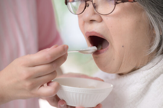 訪問介護で高齢者の食事介助をするホームヘルパー、在宅介護、食事支援、食べることをサポートする女性介護職のイメージの顔無しの口元クローズアップ